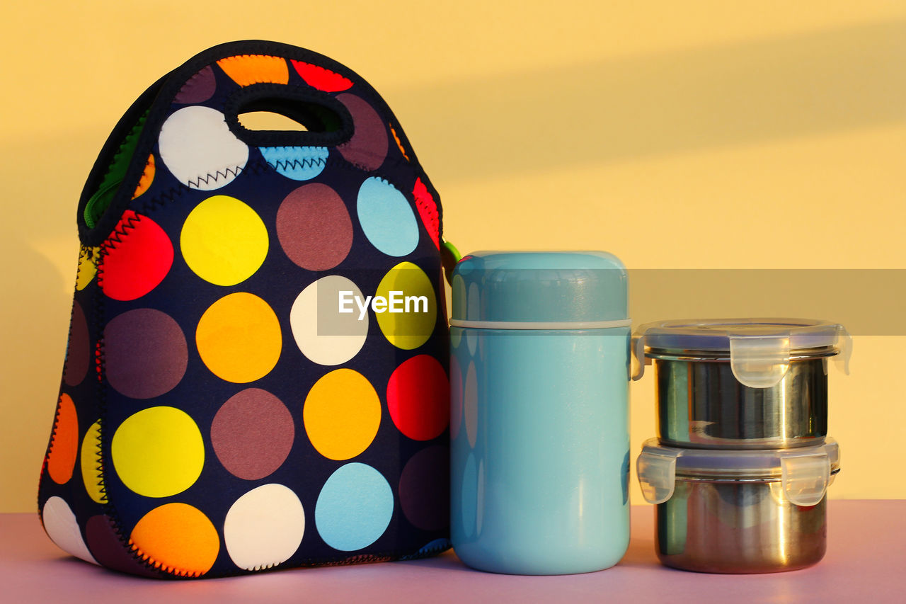 Snack on a break with a lunchbox. colorful handbag, blue thermos and two metal containers with food