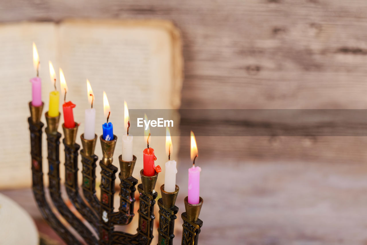 High angle close-up of lit colorful candles on wooden table