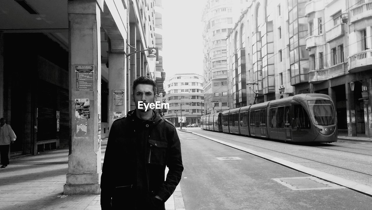 Portrait of man standing on footpath in city