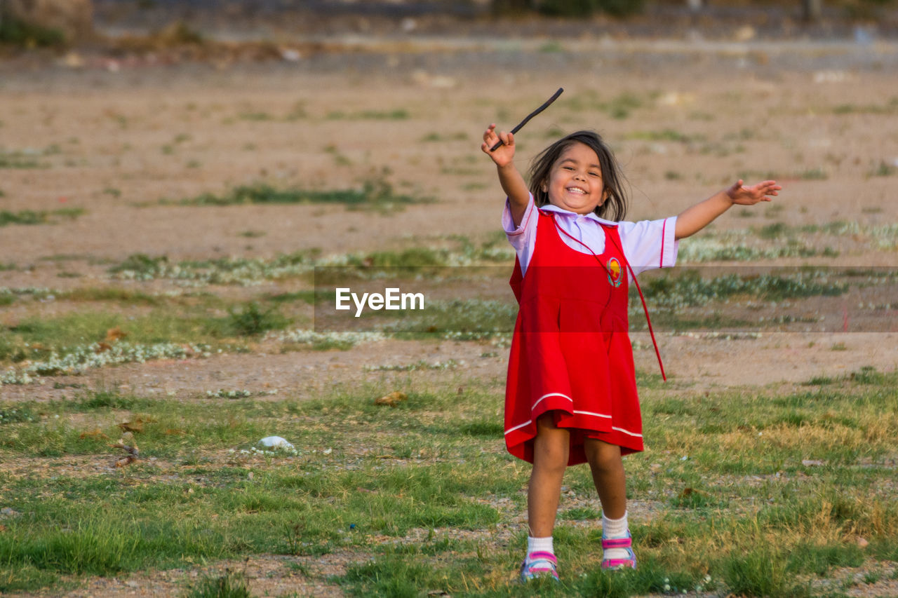 Portrait of cheerful girl playing on field