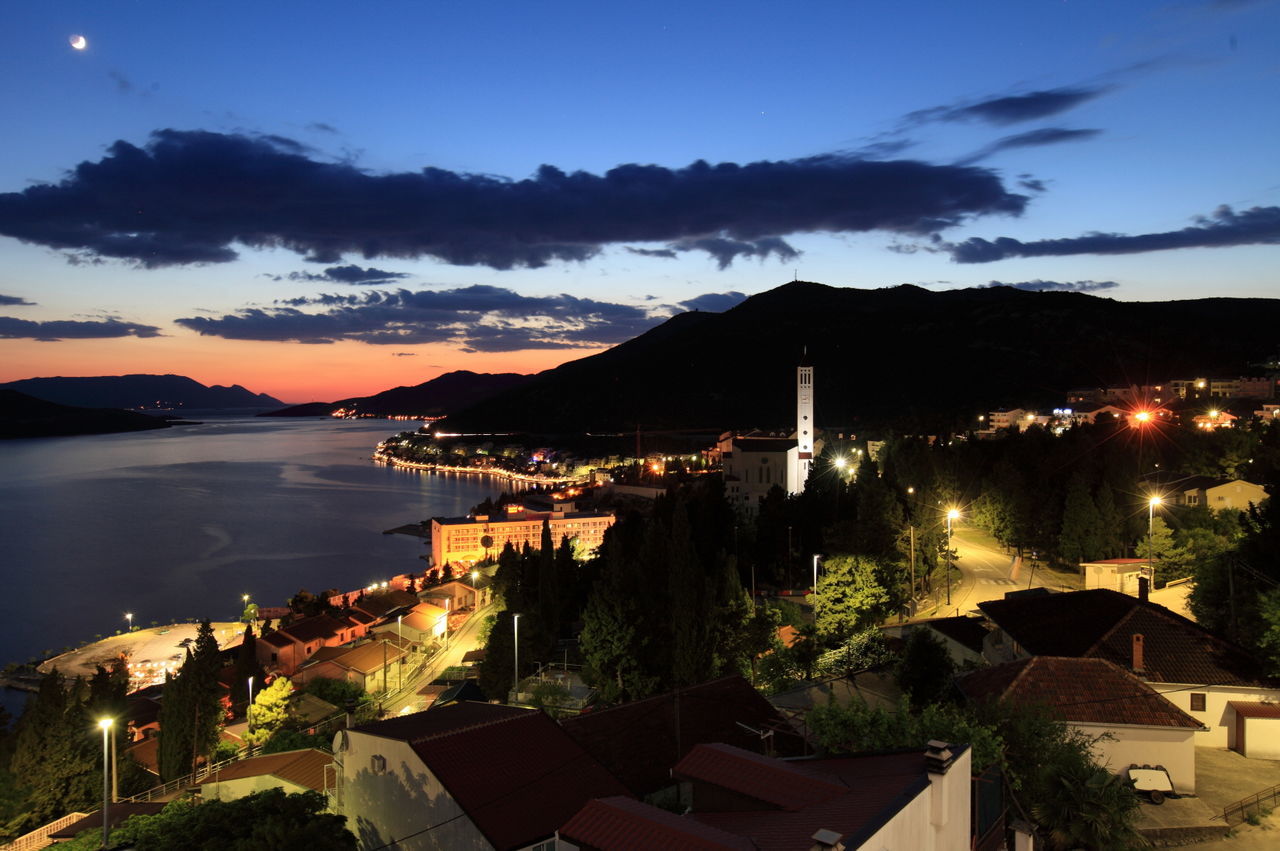 Town by sea against sky at sunset