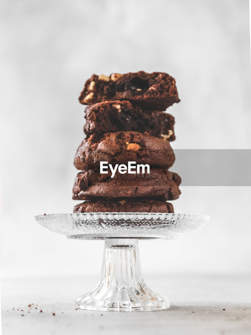 Close-up of stack of chocolate chip cookies on crystal glass stand on table 