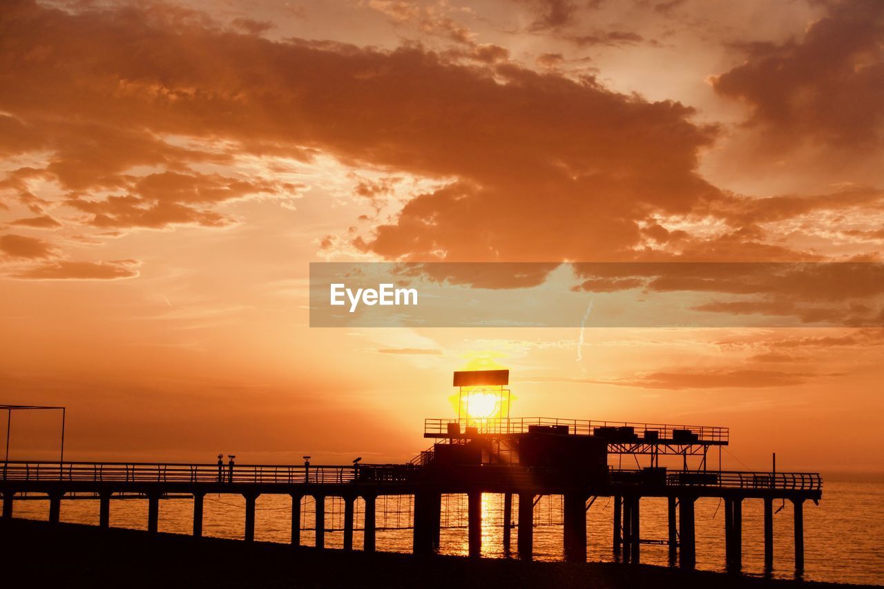 Silhouette built structure by sea against sky during sunset