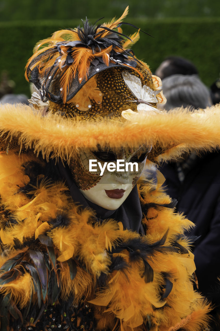 feather, clothing, costume, celebration, tradition, arts culture and entertainment, disguise, mask, one person, mask - disguise, animal, adult, outdoors, day, animal themes, carnival, headwear, animal wildlife, focus on foreground, event, nature