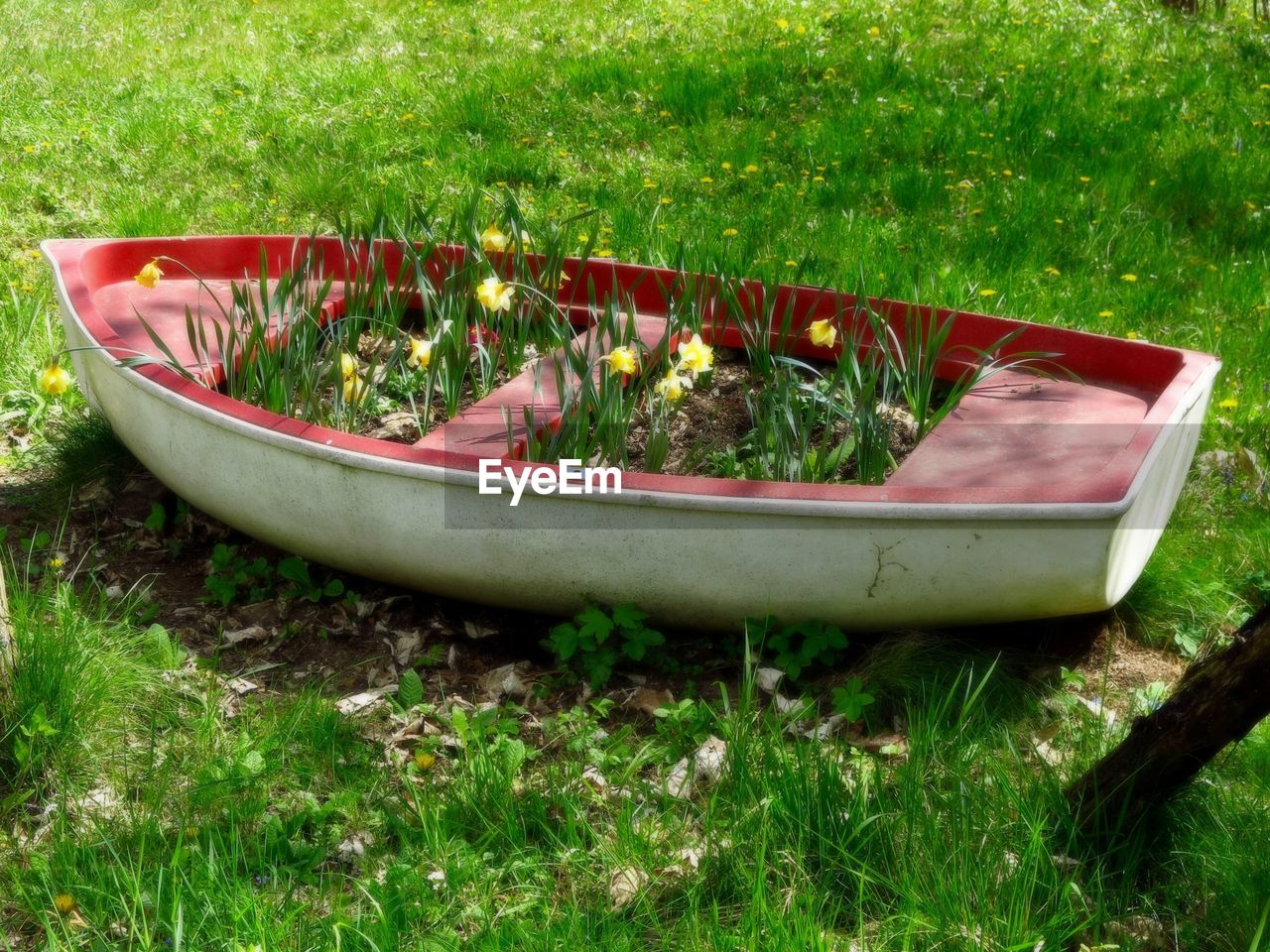 ABANDONED BOAT MOORED ON GRASS BY WATER