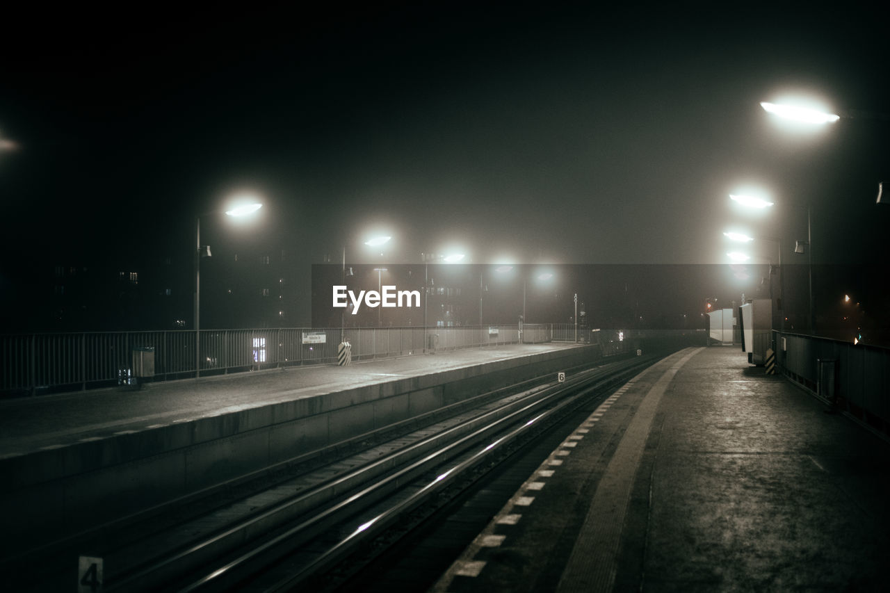 Empty illuminated railroad station at night during foggy weather