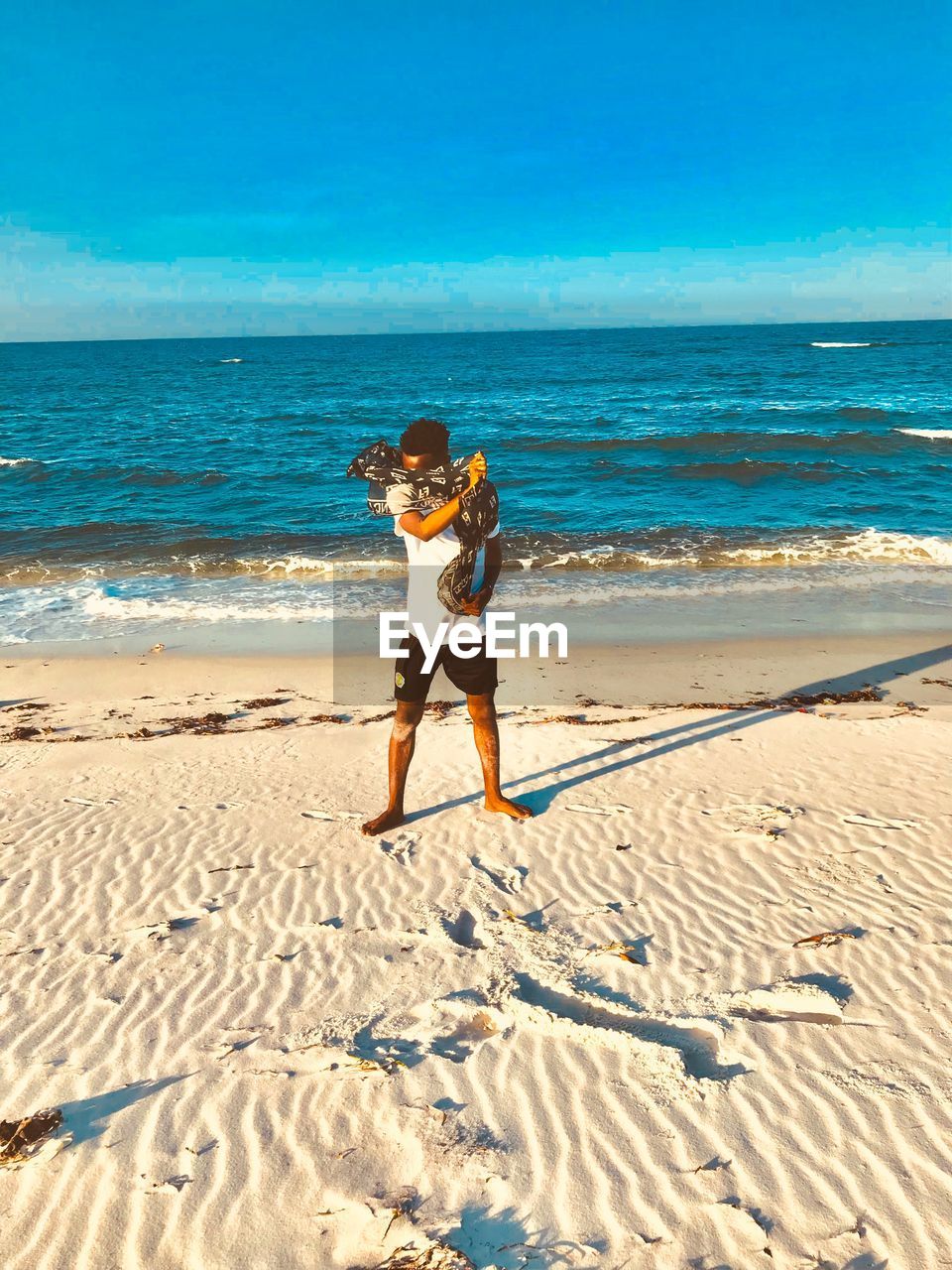 land, beach, sea, water, sand, sky, full length, nature, ocean, shore, body of water, one person, holiday, vacation, trip, leisure activity, adult, beauty in nature, sunlight, horizon over water, horizon, lifestyles, sunny, day, scenics - nature, women, summer, motion, wave, clothing, coast, standing, blue, young adult, outdoors, casual clothing, travel destinations, travel, shadow, clear sky, person, female, sports, tranquility, relaxation, idyllic, child, childhood, tourism