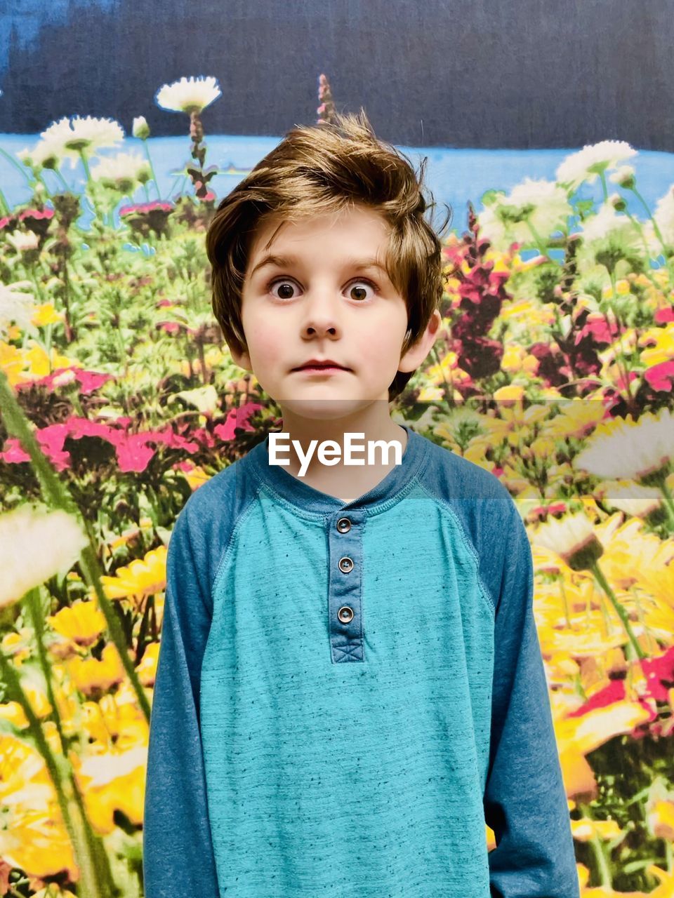 Portrait of boy standing by flowering plants