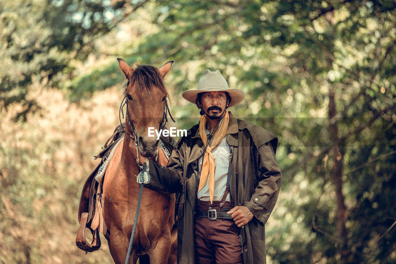 Man standing by horse in forest