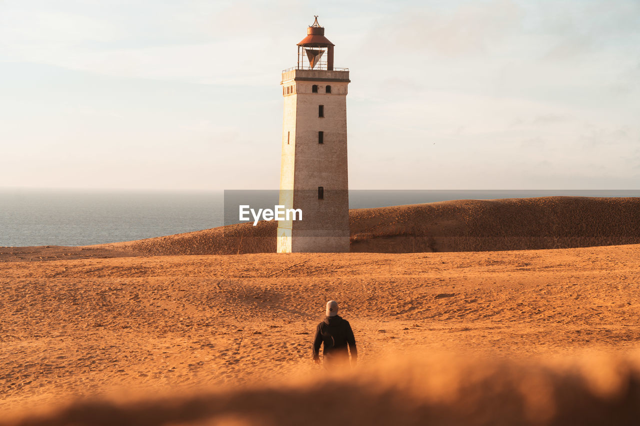 Lighthouse by sea against sky