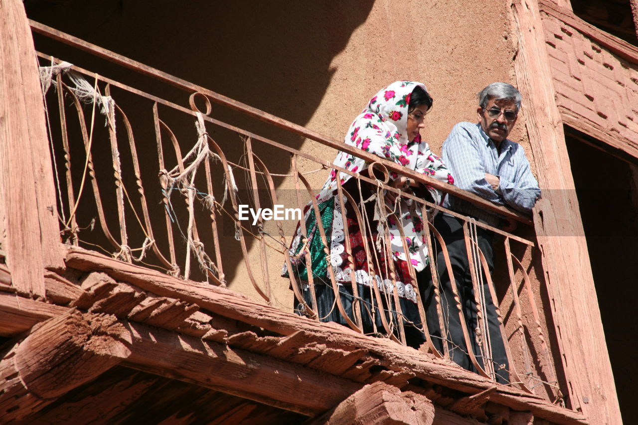 PEOPLE STANDING ON RAILING AGAINST WALL
