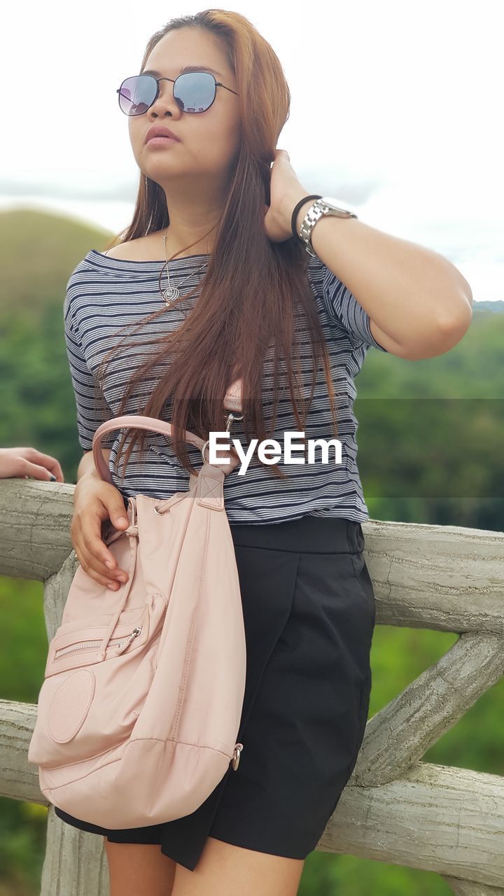 Young woman in sunglasses standing outdoors