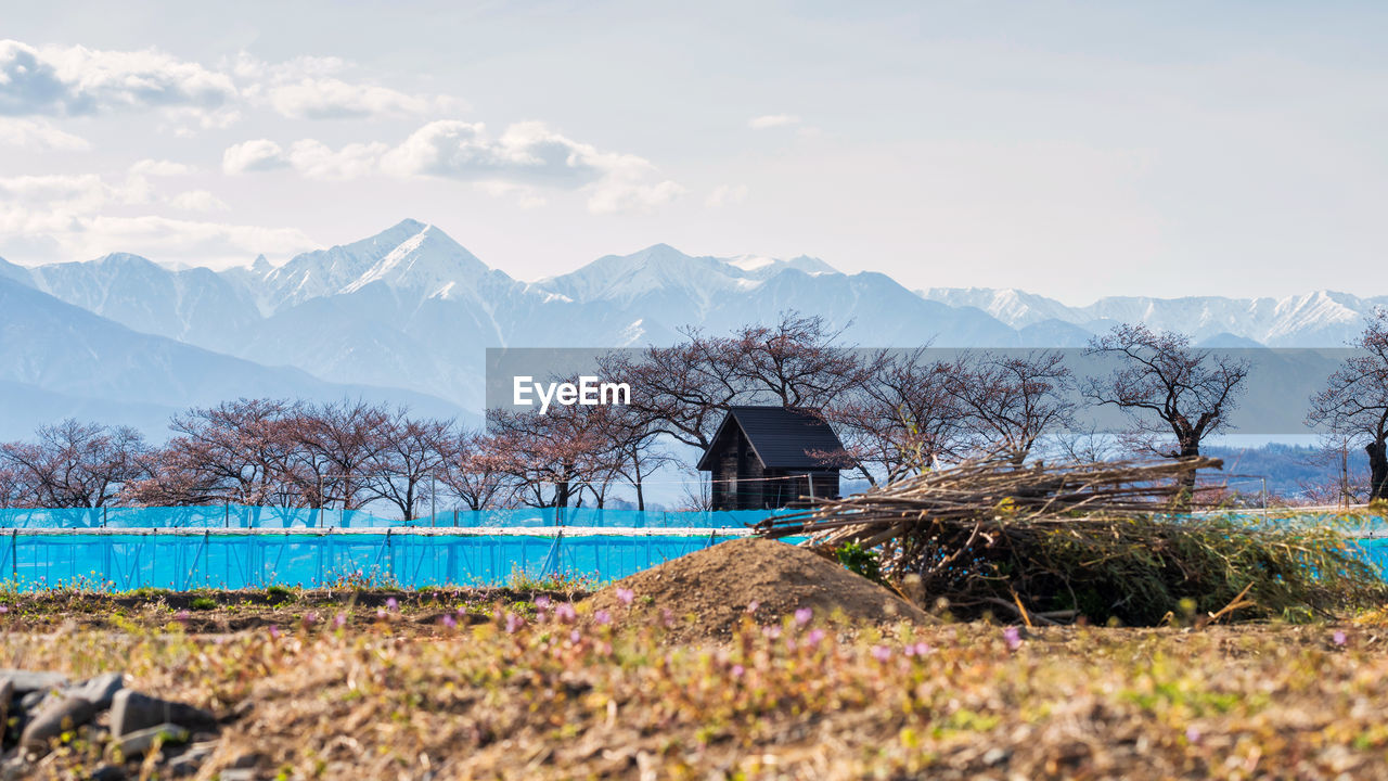 BUILT STRUCTURE ON FIELD BY MOUNTAIN AGAINST SKY