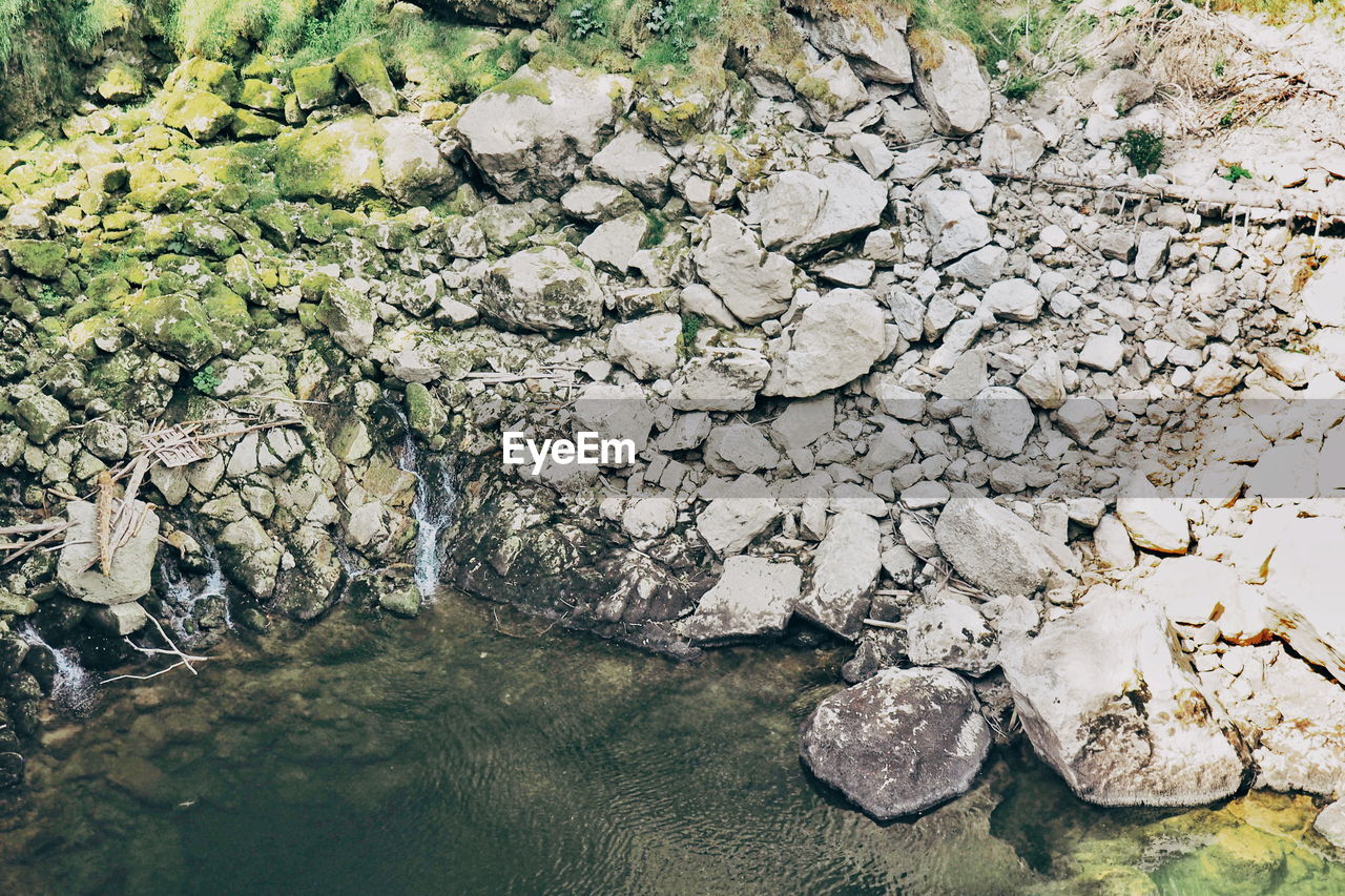 HIGH ANGLE VIEW OF STONES BY LAKE