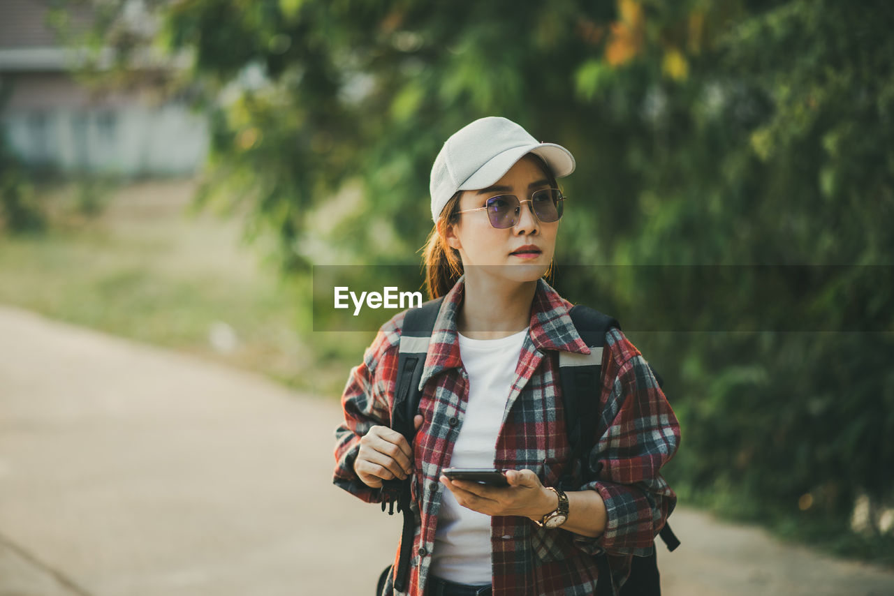 Portrait of young woman standing outdoors hold myphone 