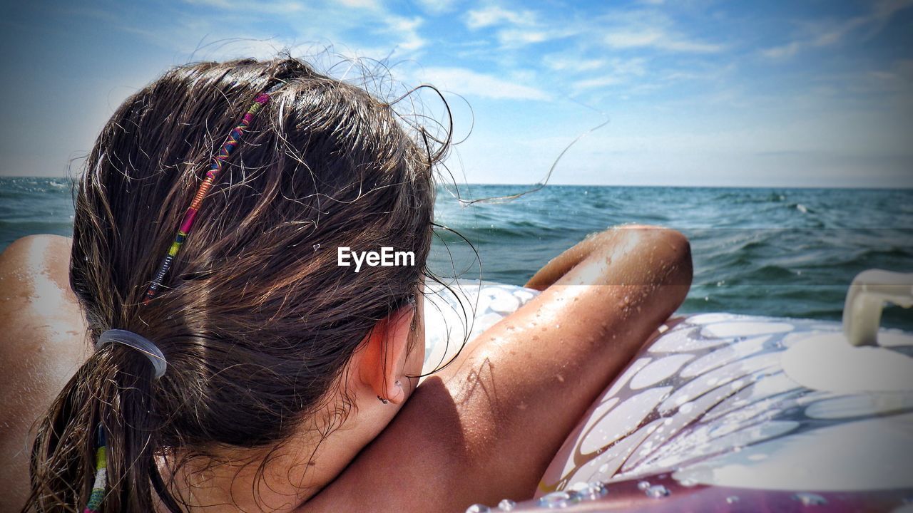 Girl in inflatable ring at sea against sky