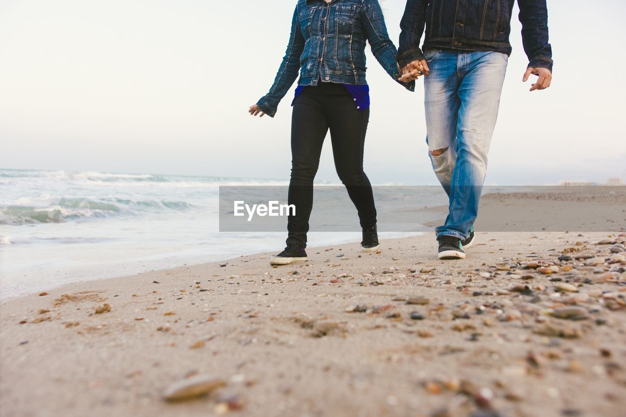 Low section of couple walking at beach