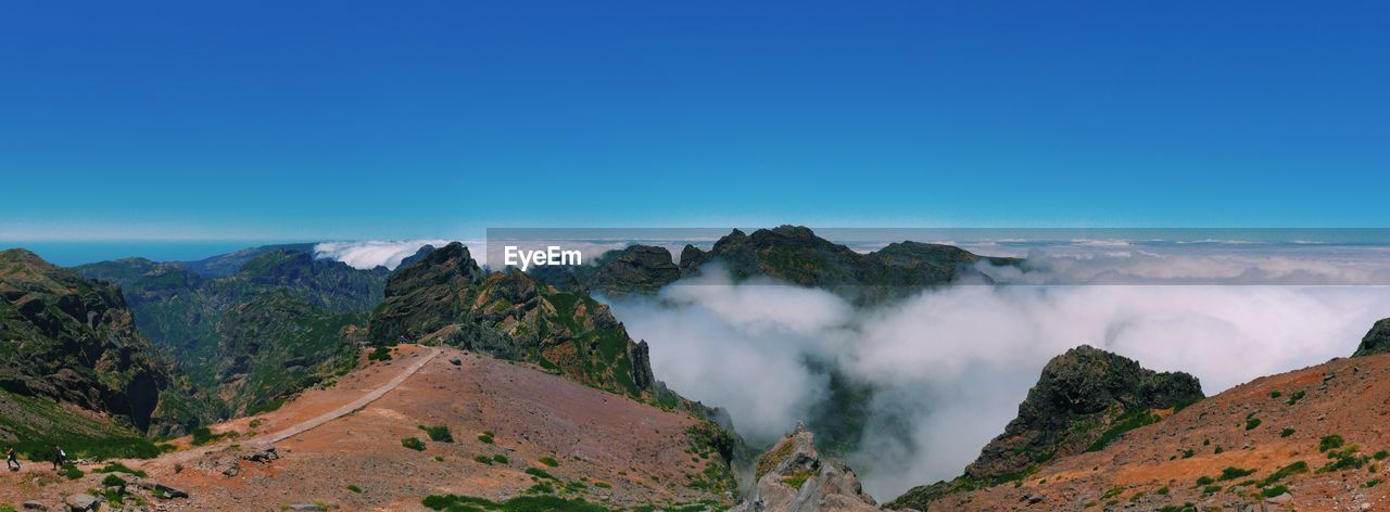 Scenic view of clouds covering mountains against blue sky