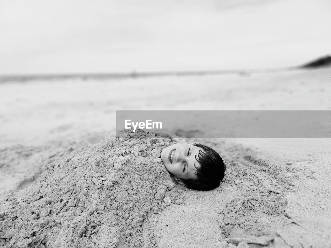High angle view of boy buried in sand at beach