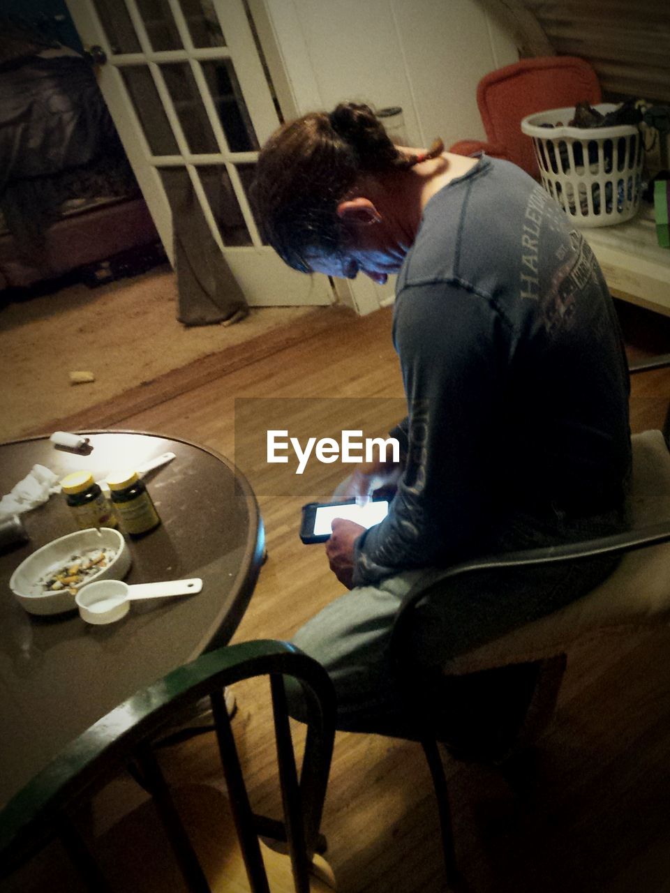 REAR VIEW OF MAN USING LAPTOP ON TABLE AT HOME