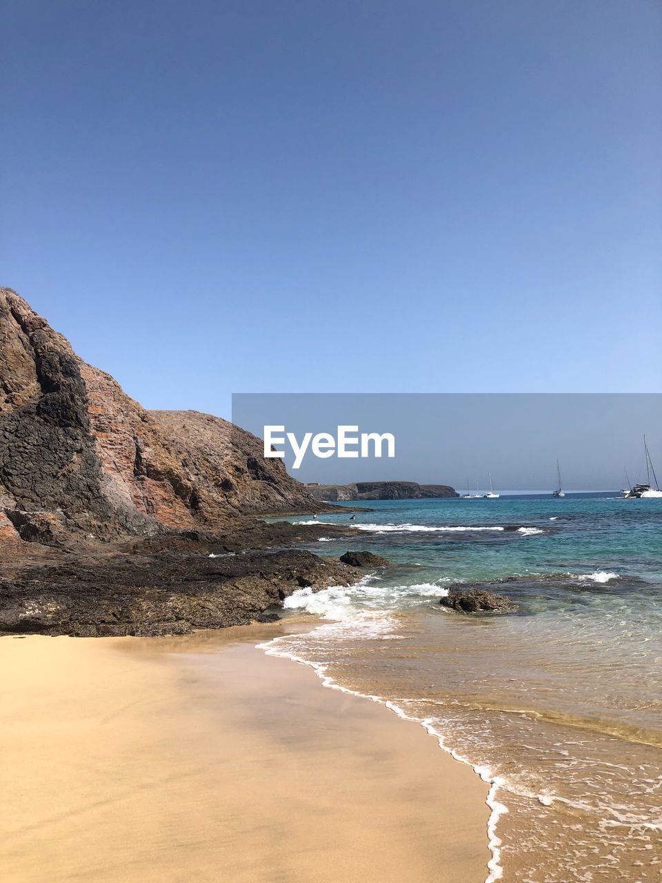 Scenic view of beach against clear blue sky