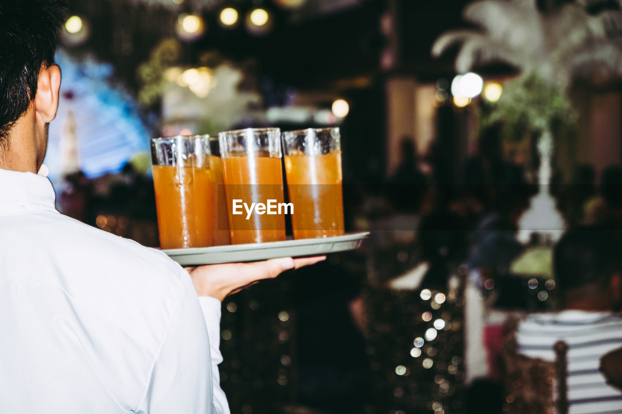 CLOSE-UP OF MAN HOLDING DRINK AT RESTAURANT