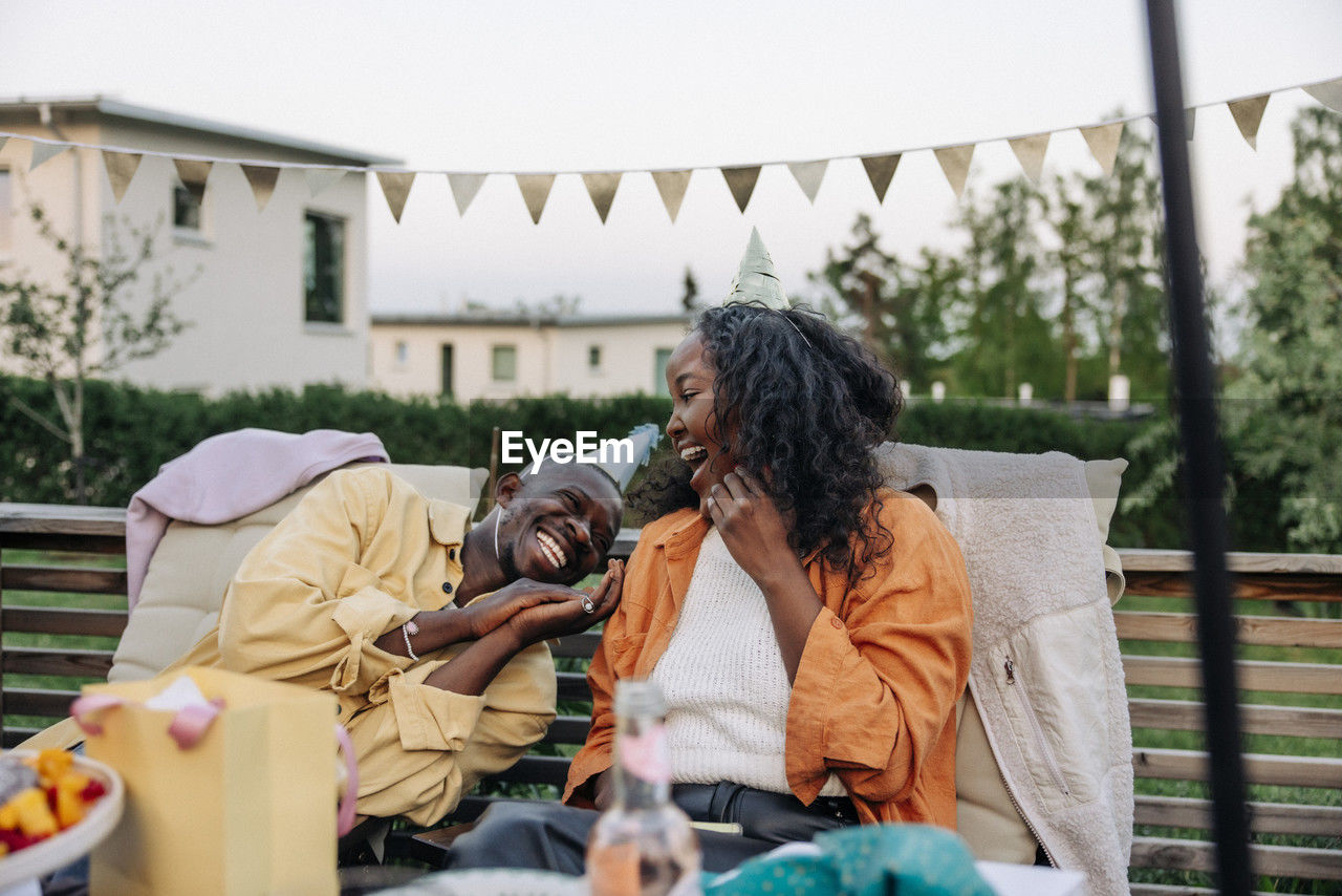 Young man laughing with female friend while sitting in back yard