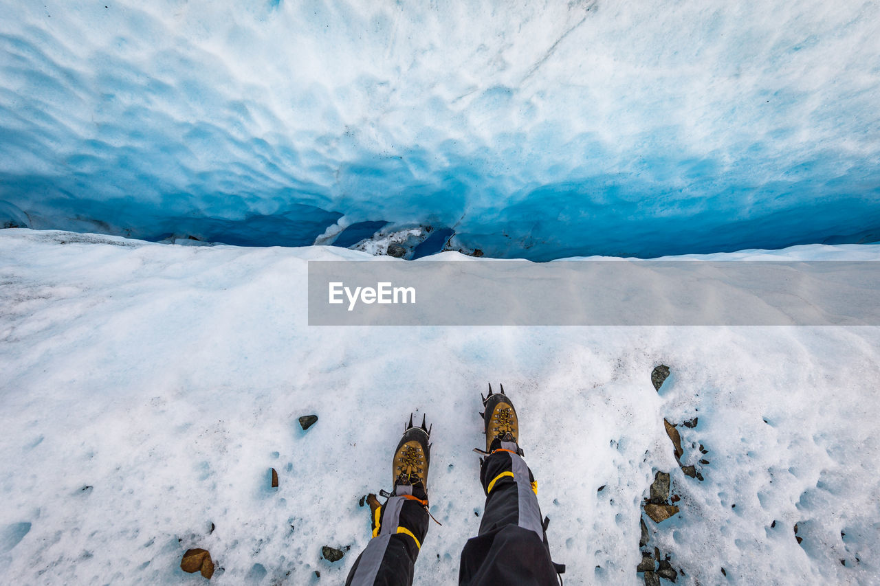 Low section of person skating on snow covered landscape