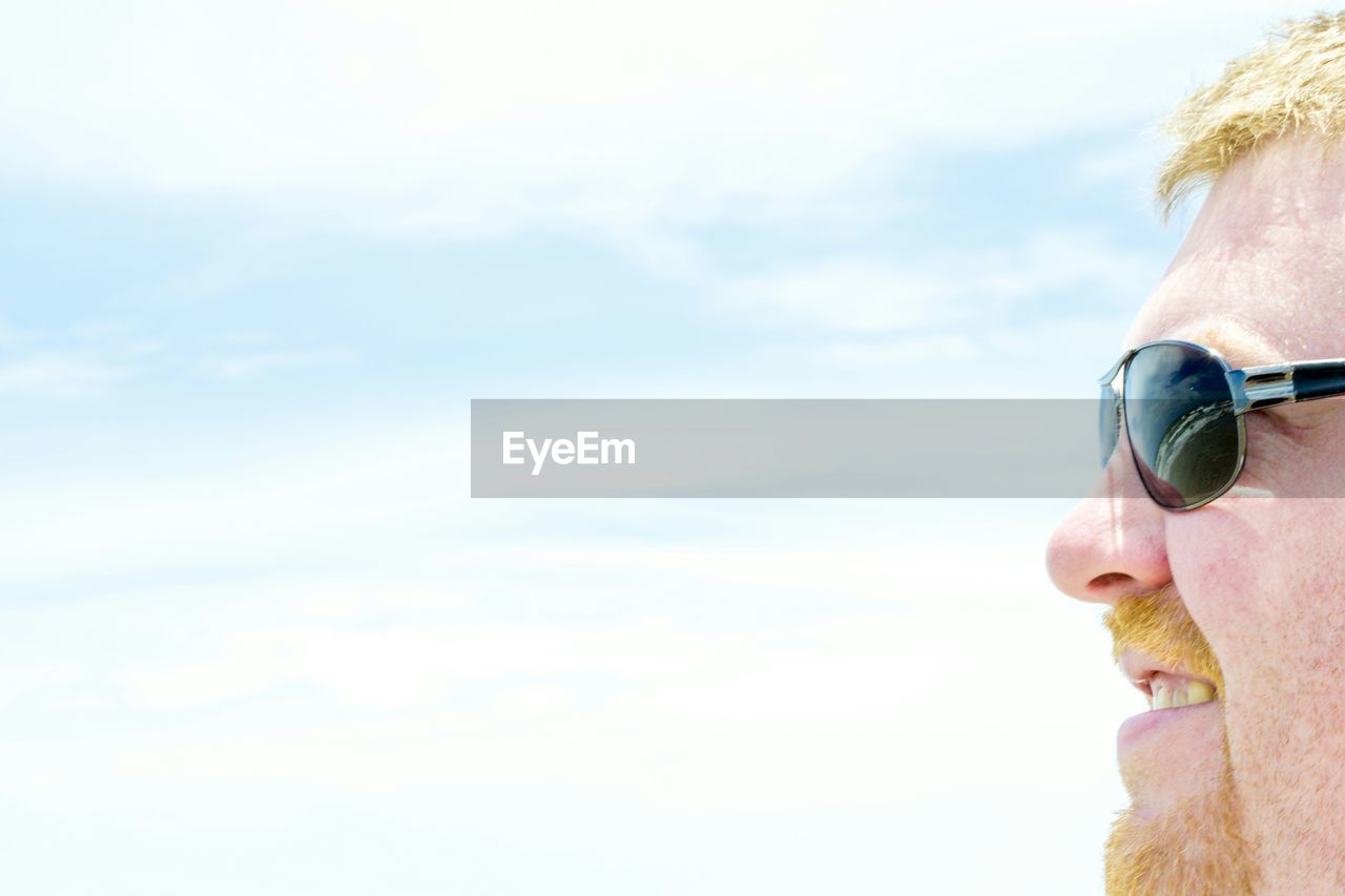 Profile view of man wearing sunglasses against sky during sunny day