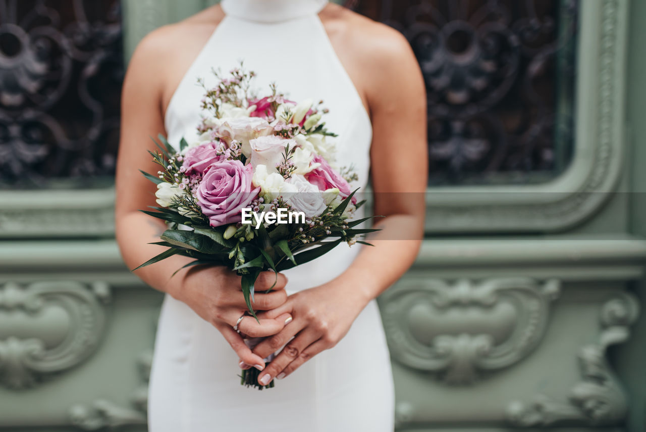 Midsection of bride holding flower bouquet