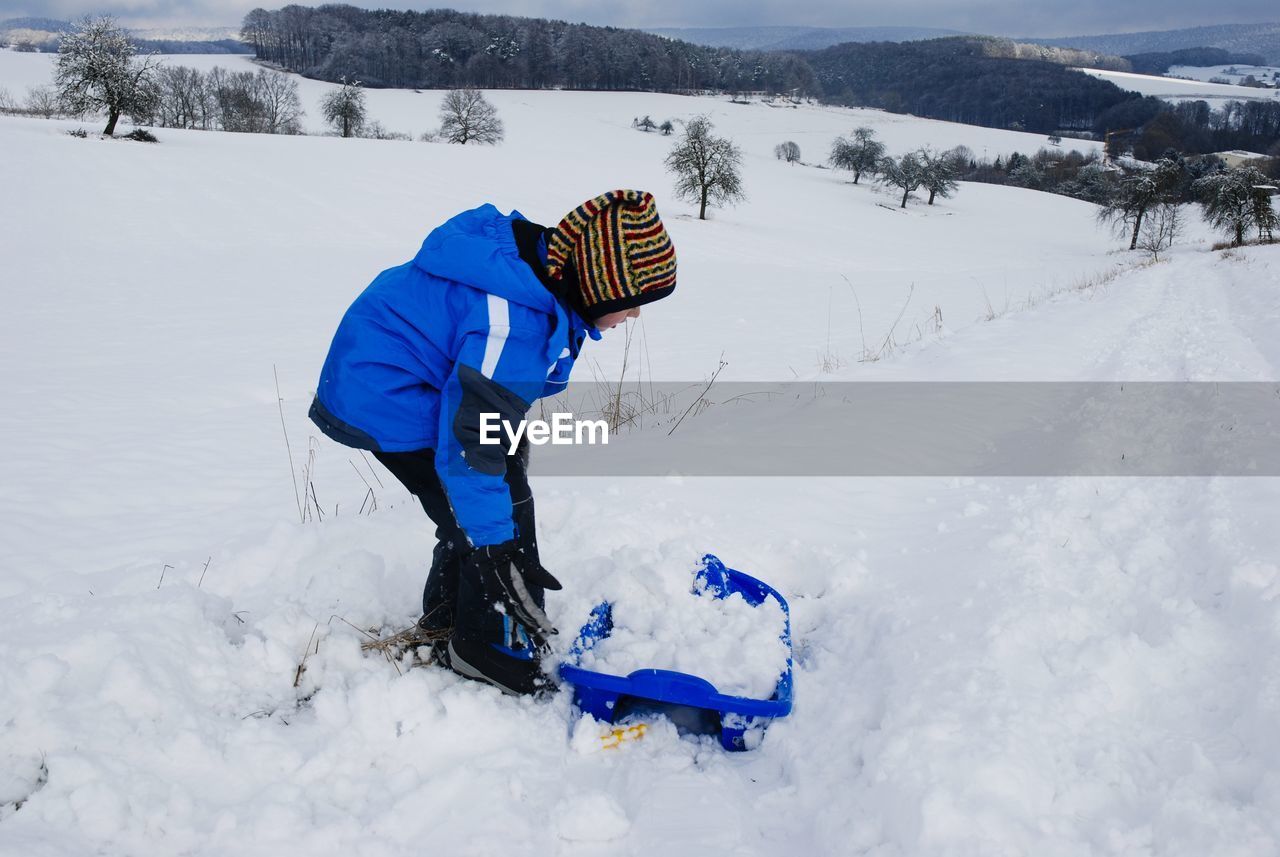 Side view of girl on snowcapped field during winter