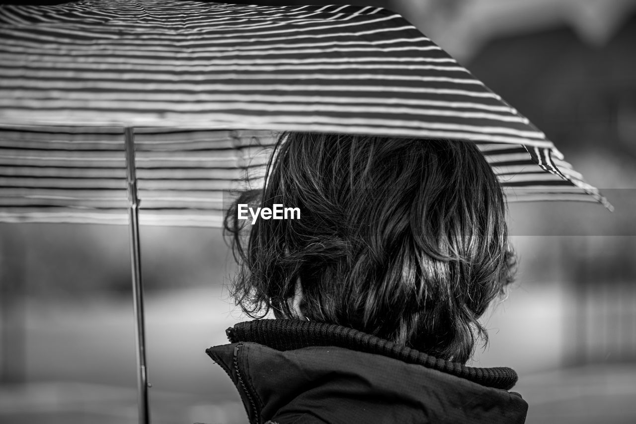 Rear view of woman holding umbrella outdoors