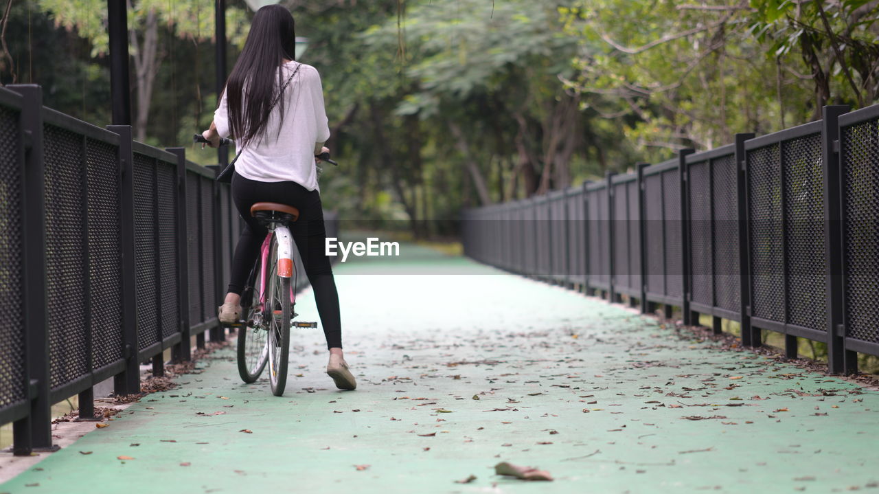 Rear view of woman walking on bridge in city