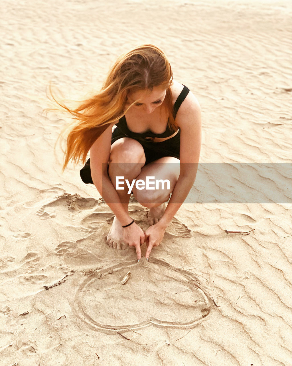 Young woman making heart shape on beach