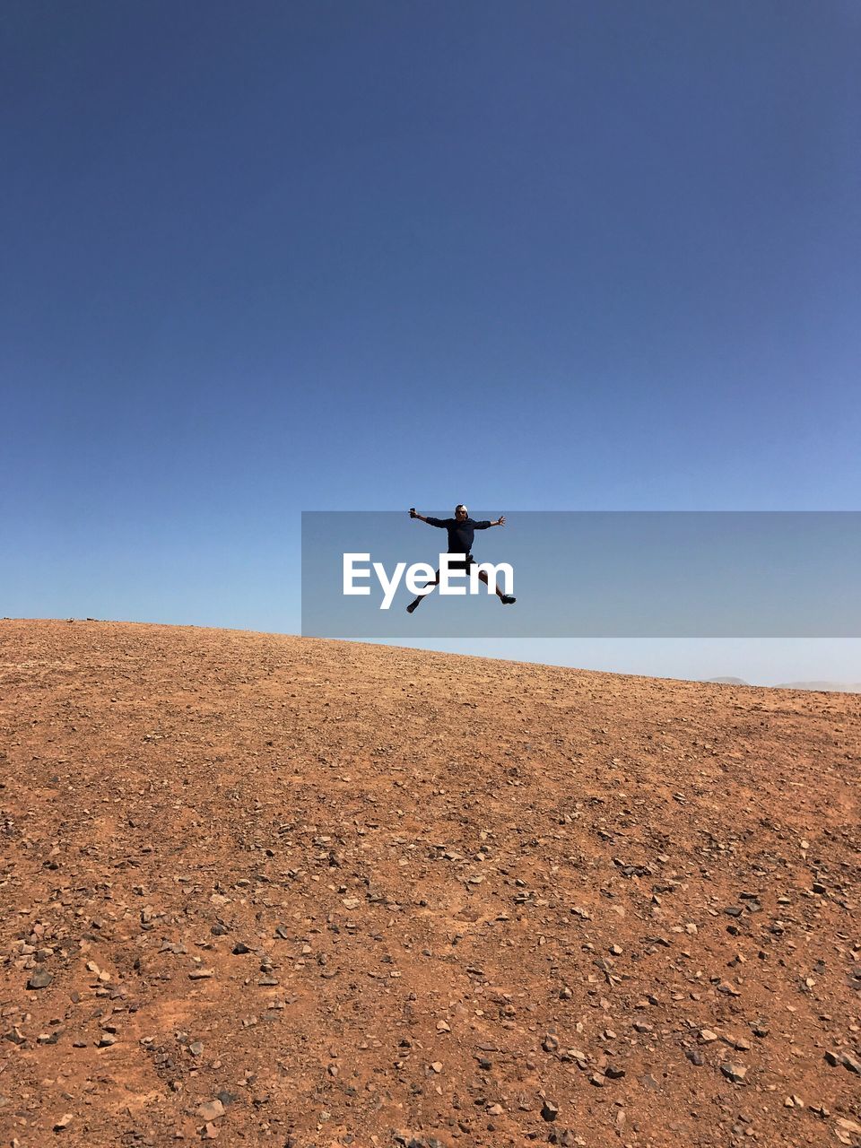 MAN JUMPING FLYING AGAINST CLEAR BLUE SKY