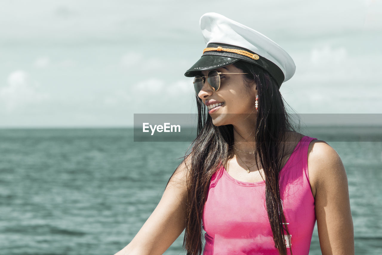 A woman on top of a boat against the sea in the background. 