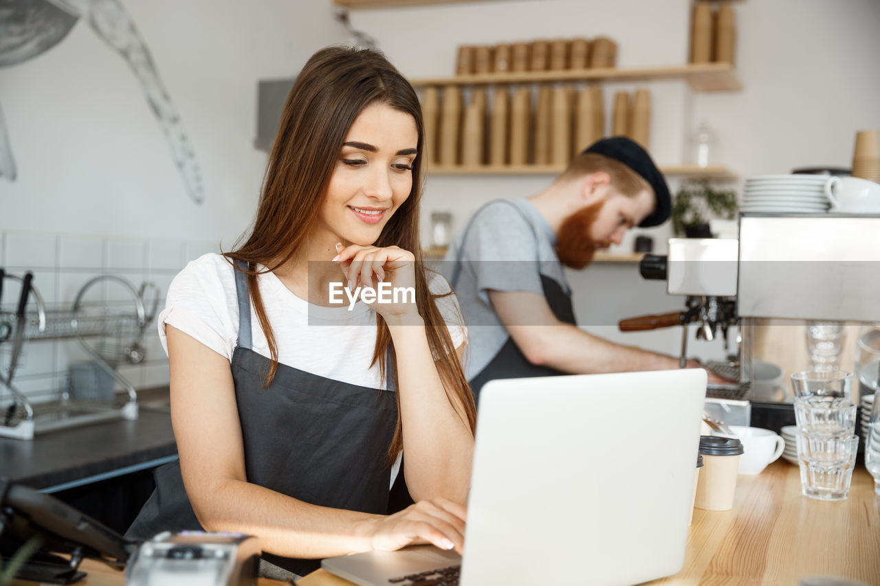 young woman using laptop while sitting on table