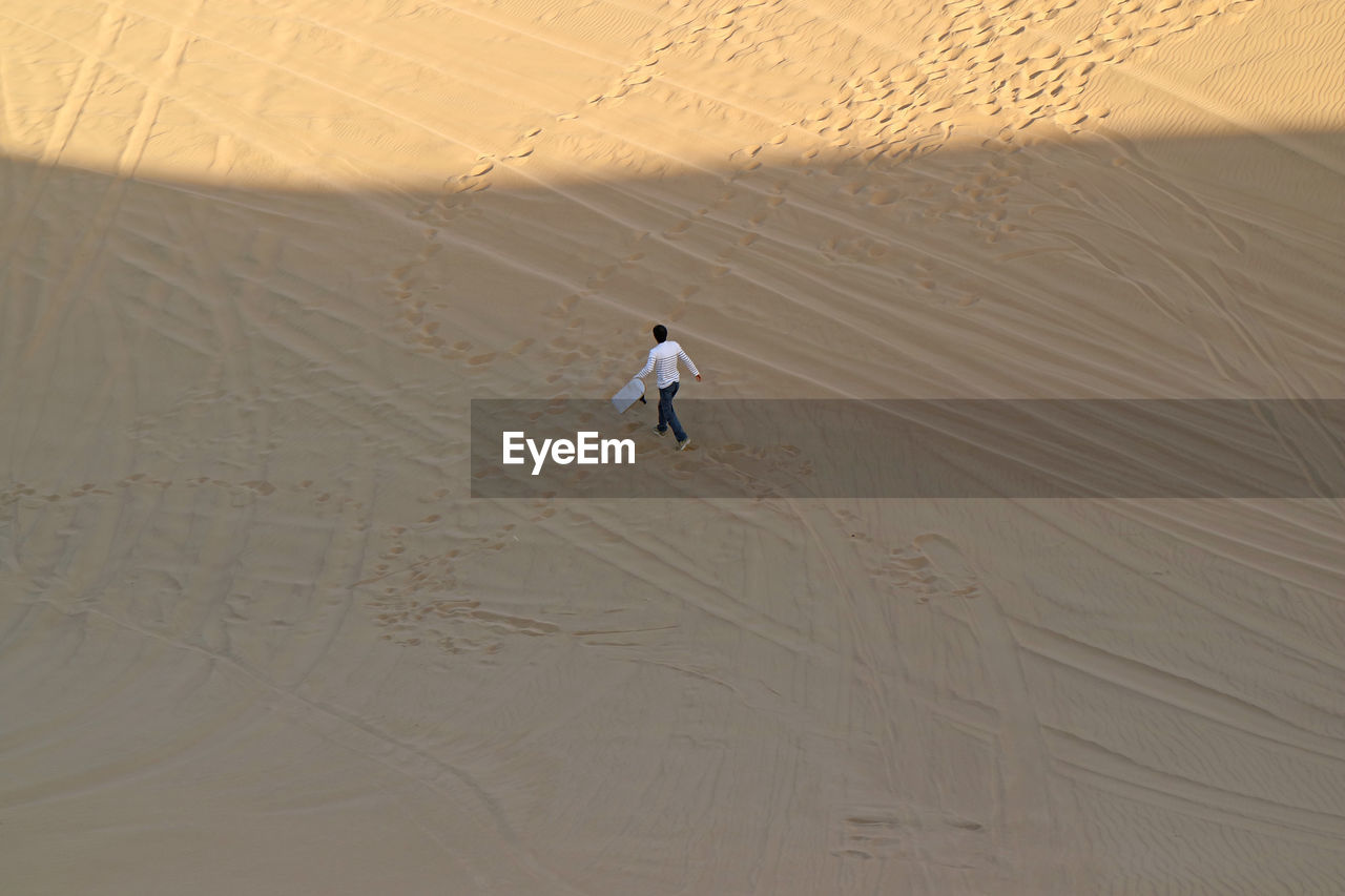 Aerial view of man walking on sand dune