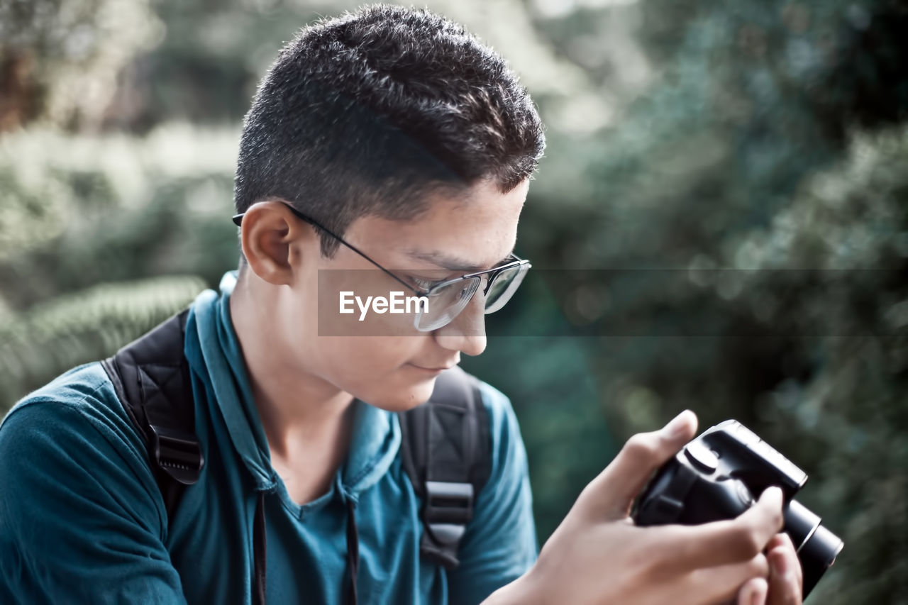 Close-up of teenage boy holding camera