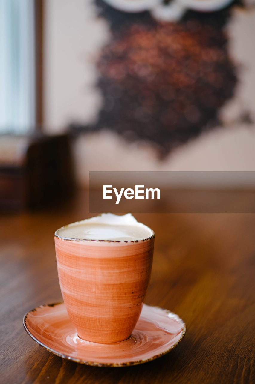 CLOSE-UP OF COFFEE CUP ON WOODEN TABLE