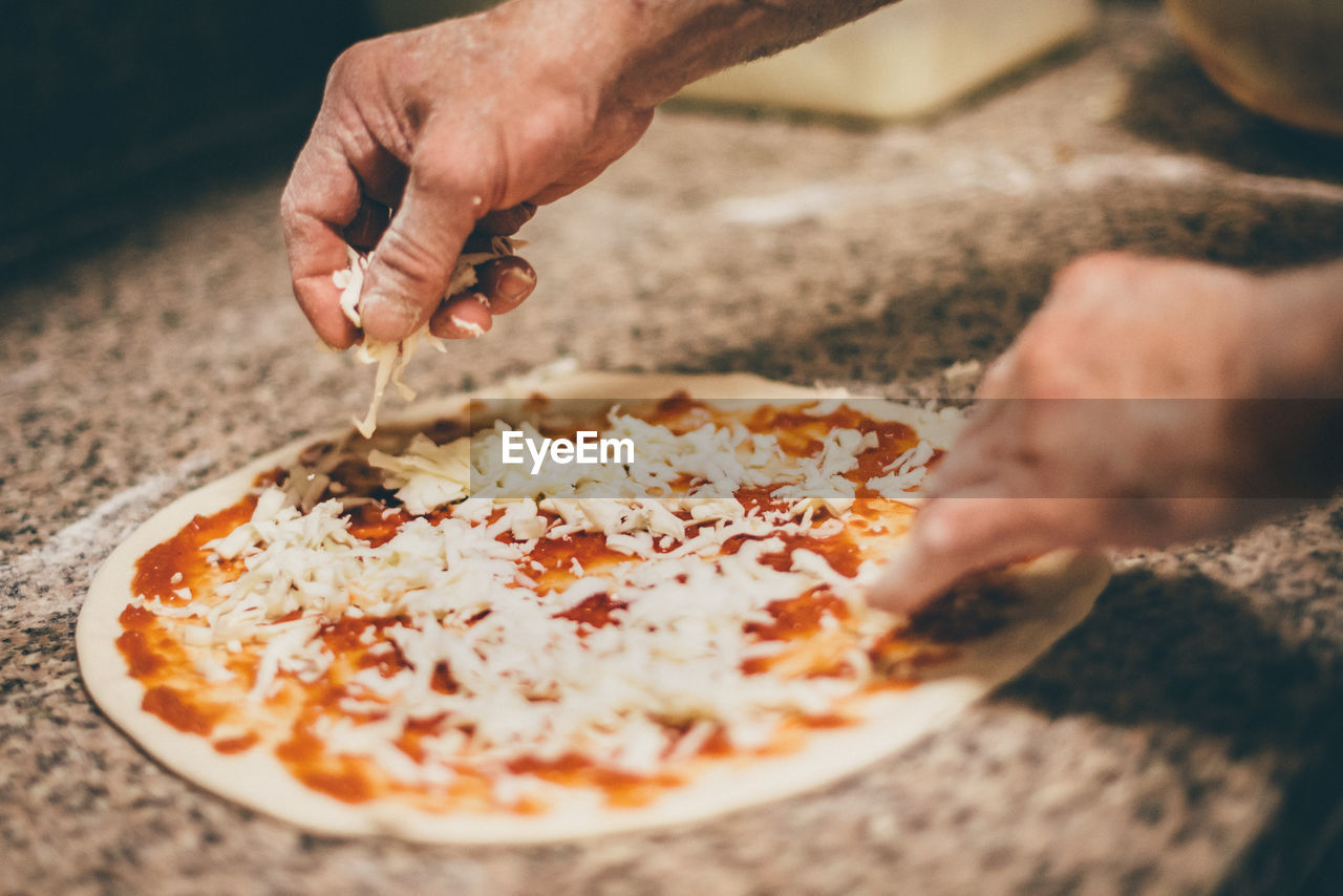 CLOSE-UP OF PERSON HAND HOLDING PIZZA