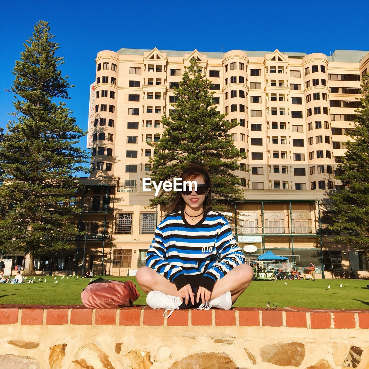 PORTRAIT OF YOUNG WOMAN AGAINST BUILT STRUCTURE