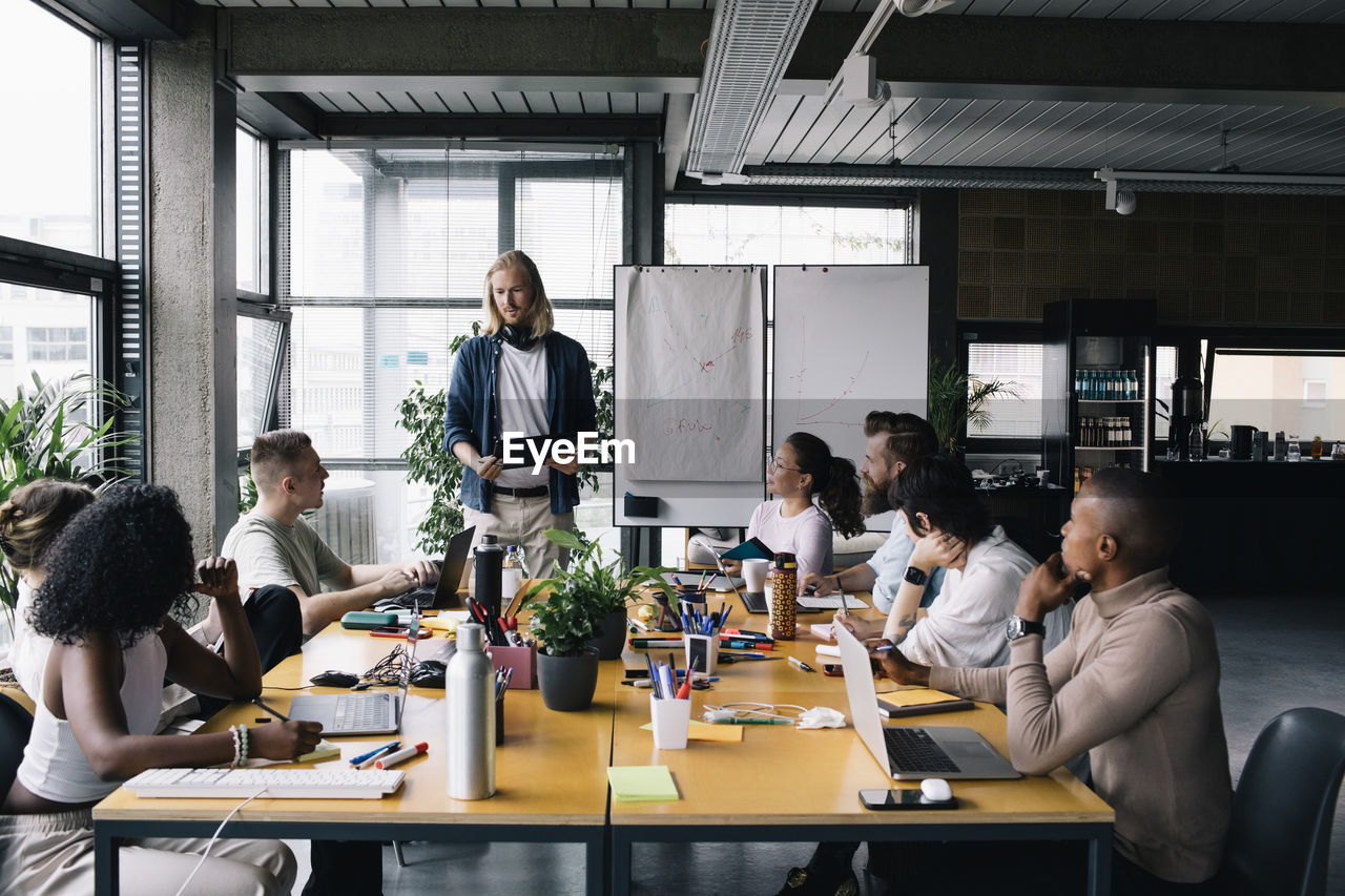 Businessman giving presentation to colleagues in meeting at office