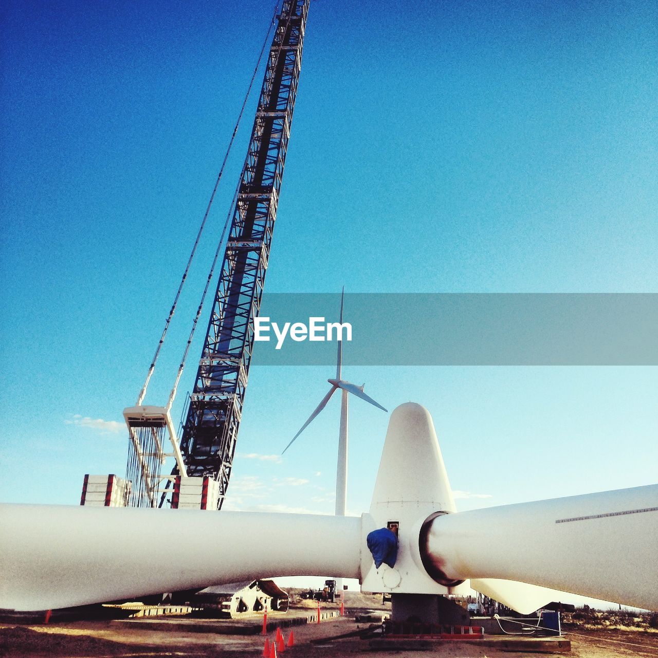 LOW ANGLE VIEW OF CRANES AGAINST CLEAR BLUE SKY