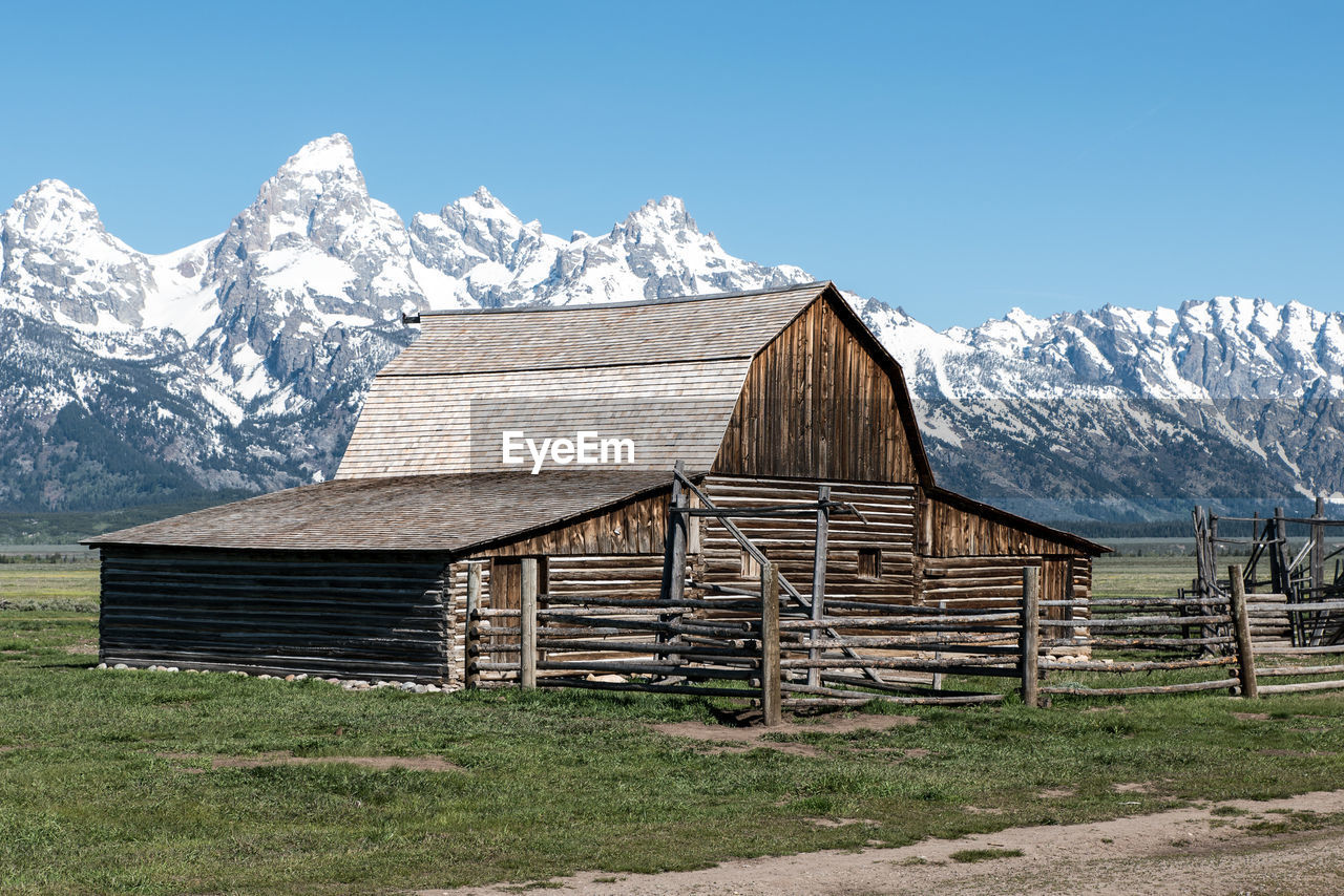 Barn on field against snowcapped mountains