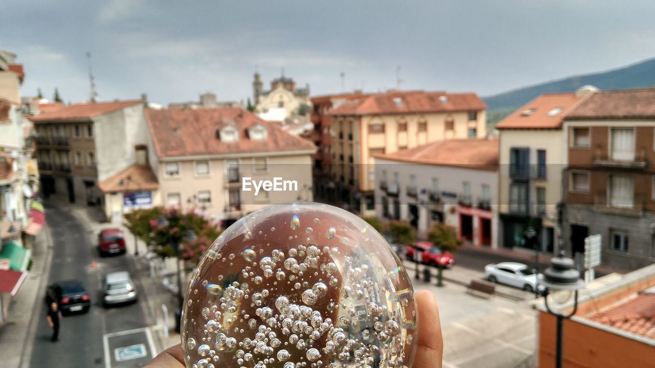 Cropped image of person holding crystal ball in city