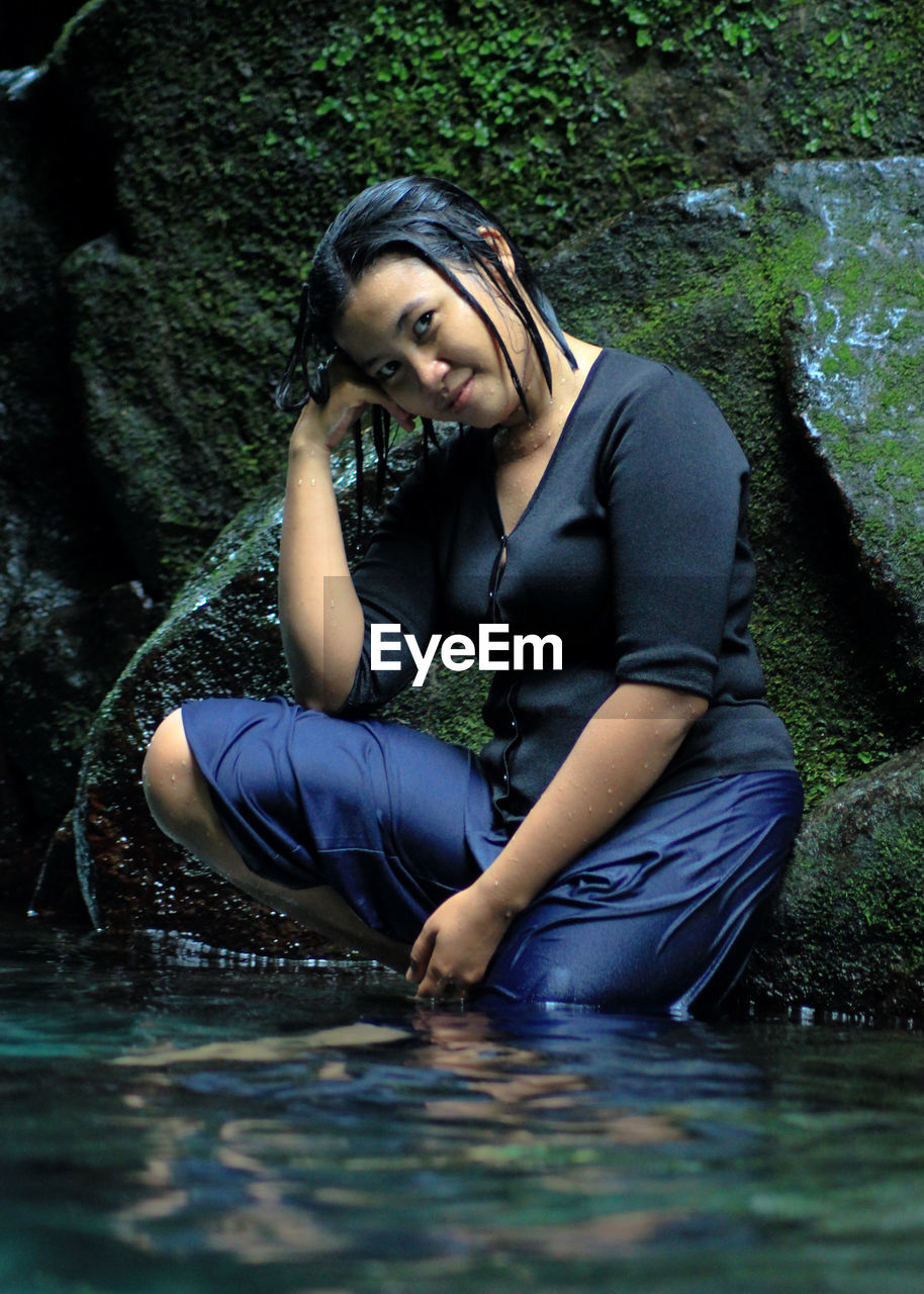 Portrait of young woman sitting in lake