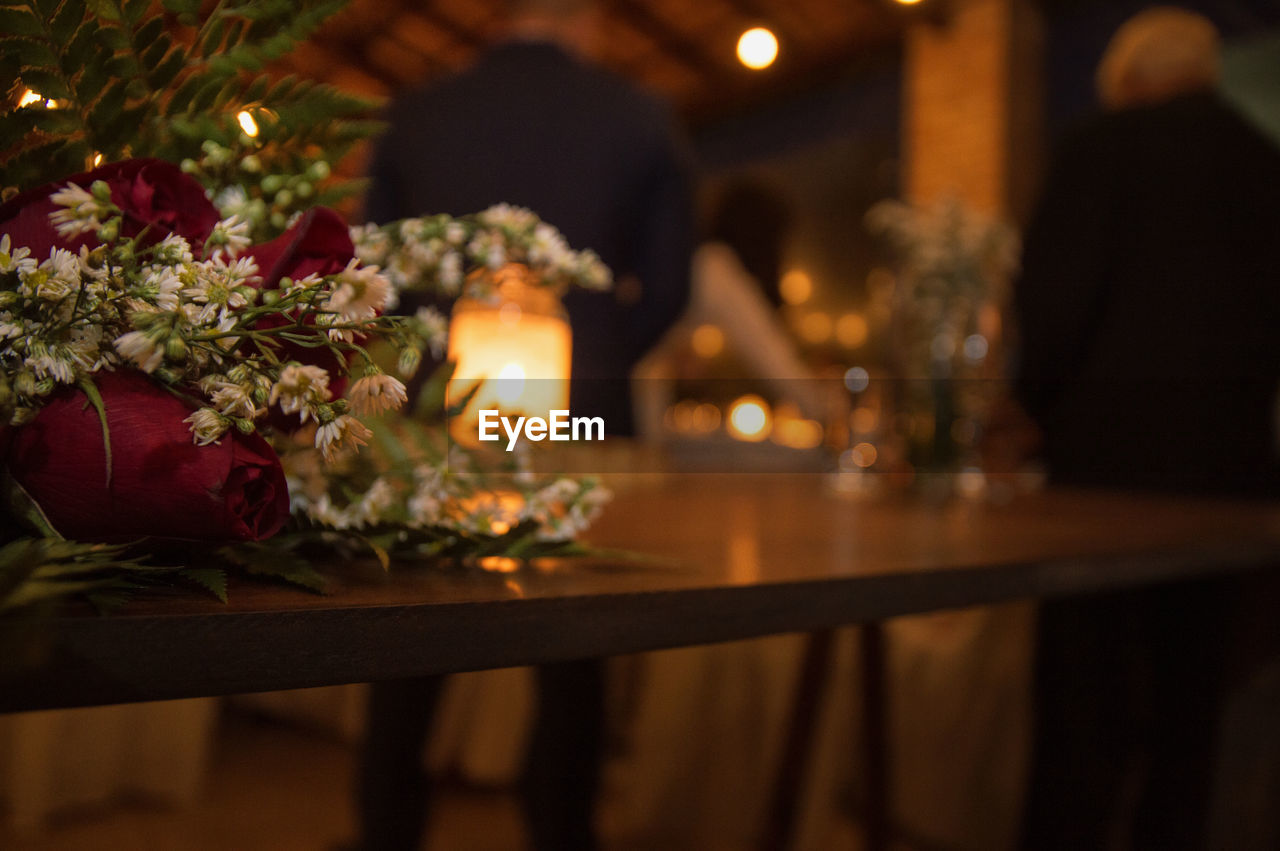 CLOSE-UP OF FLOWER VASE ON TABLE AT NIGHT