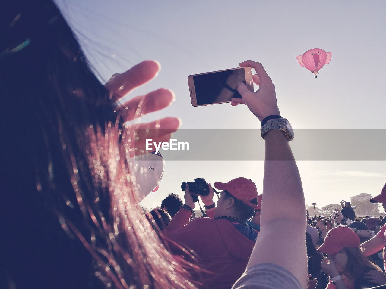 CLOSE-UP OF MAN PHOTOGRAPHING WITH MOBILE PHONE AGAINST SKY