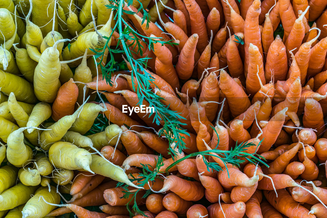 Full frame shot of yellow and orange carrots for sale at farmers market stall